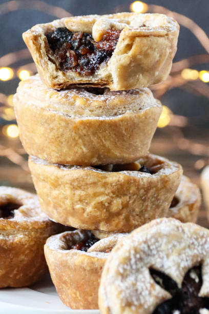 istock Full frame image of stack homemade mince pies dusted with icing sugar, illuminated fairy lights background, focus on foreground 1370907894