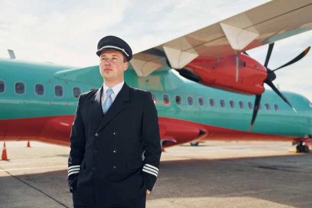 istock Pilot in formal black uniform is standing outdoors near plane 1370908118