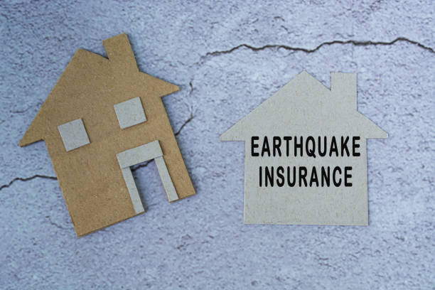 Earthquake insurance text on paper house model. Home insurance concept. stock photo