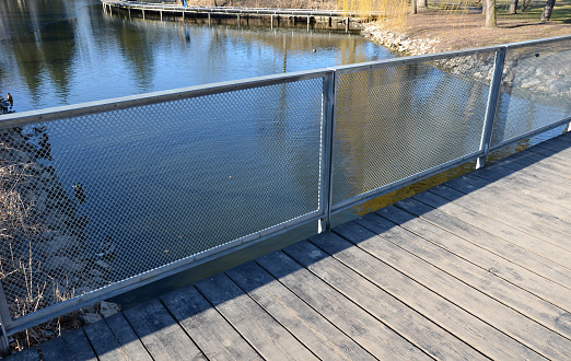 metal galvanized railing on the bridge. The filling is formed by a metal mesh of expanded metal. transparent railing better view of the river pond water,