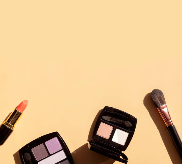 istock Decorative cosmetics for make-up with sun shadows on beige background flat lay top view. Eyeshadow palette, red lipstick, makeup brushes. Beauty fashion background. Makeup professional Products 1370912330