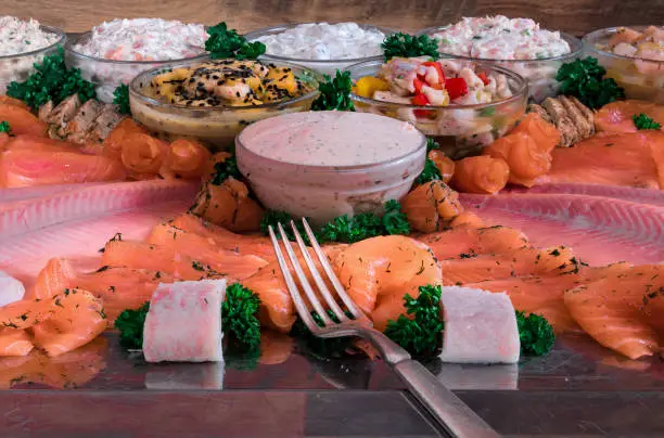 Photo of Arrangement of various different fish gourmet food, nicely arranged on a steel plate with a fork