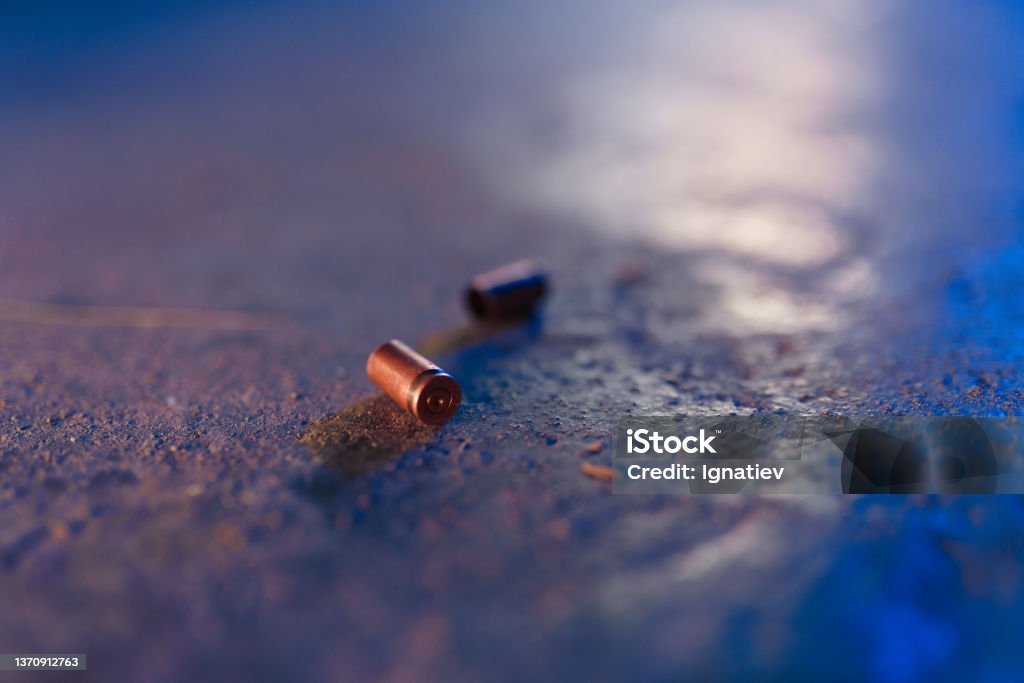 Two bullet casings on the floor in blue light Two bullet casings on the floor in blue light in close up Bullet Stock Photo