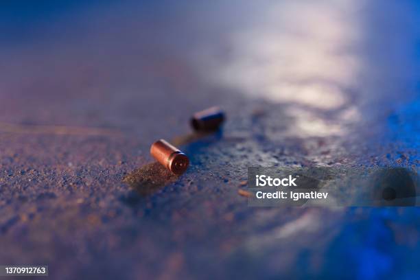 Two Bullet Casings On The Floor In Blue Light Stock Photo - Download Image Now - Bullet, Crime Scene, Bullet Cartridge
