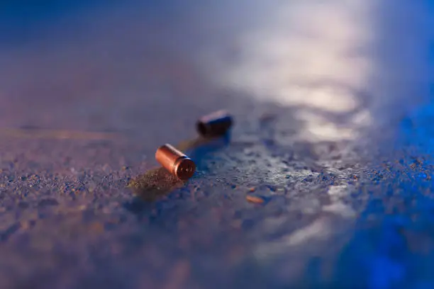 Two bullet casings on the floor in blue light in close up