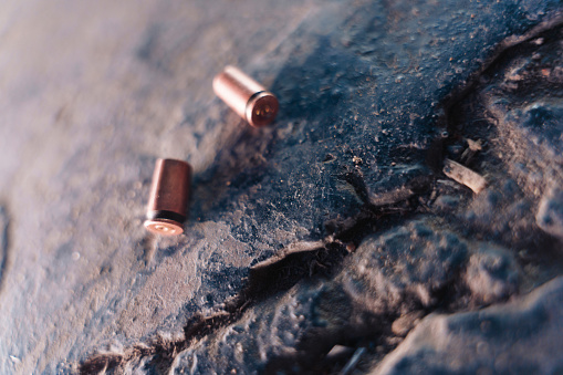 Two lightened bullet casings on a black stone in close up, macro photo