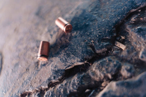 Two lightened bullet casings on a black stone in close up, macro photo