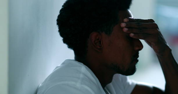 istock Black man feeling stress, african descent sitting on floor rubbing face with hand feeling worry and preoccupation, mental illness concept 1370912891