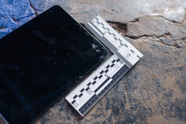 A digital tablet on a stoned floor at the crime scene with a special ruler next to it in close-up A digital tablet on a stoned floor at the crime scene with a special ruler next to it in close-up evidence photos stock pictures, royalty-free photos & images