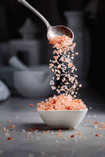 istock Pink salt in crystals is poured into a small white bowl. 1370913227