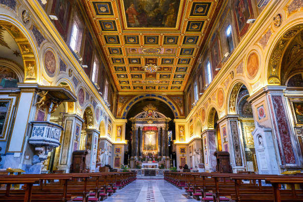 The majestic central nave of the Basilica of San Lorenzo in Lucina in the heart of Rome A suggestive wide view of the central nave inside the Basilica di San Lorenzo in Lucina (Basilica of St. Lawrence in Lucina), in the Rione Colonna (Colonna District) in the heart of the Eternal City. Originally built in the 4th century, this ancient church was consecrated by Pope Sixtus III in the year 440. It was rebuilt in 1130 during the pontificate of Pope Paschal II and transformed into its current form with a single nave in the 17th century, in baroque style. In the background, above the main altar, the painting of the Crucifix, by the artist Guido Reni (1575-1642). In 1980 the historic center of Rome was declared a World Heritage Site by Unesco. Super wide angle image in high definition format. san lorenzo rome photos stock pictures, royalty-free photos & images