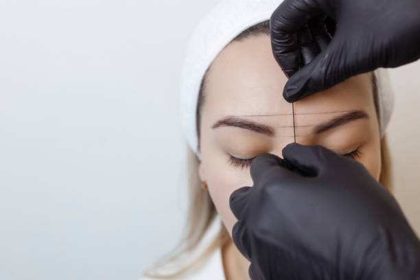 istock Eyebrow tattooing .Permanent eyebrow makeup master applies the contour with thread on the client's eyebrow 1370919845