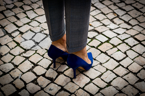 A businesswoman  climbs a set of concrete steps.  The steps are surrounded by the high rise buildings of a madern city.