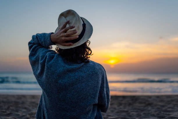 istock Unrecognizable young woman in hat enjoying sunset on the beach 1370924518