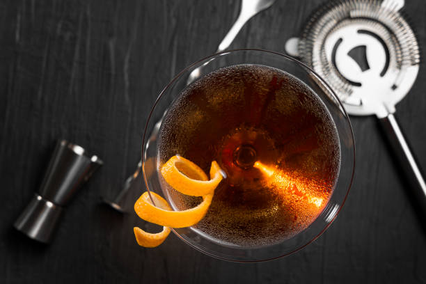 манхэттенский коктейль с оранжевой изюминкой в качестве гарнира. вид сверху - manhattan cocktail стоковые фото и изображения