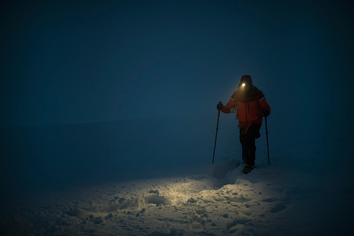 Brave mountaineer hiking in the night in winter.