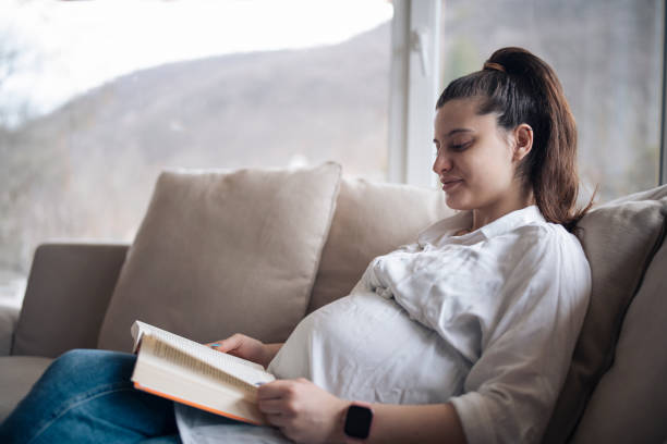 istock Pregnnat woman at home reading a book. 1370929386