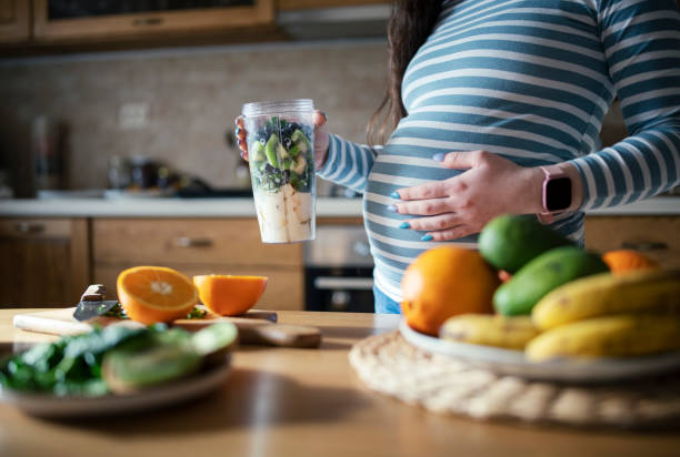 young pregnant woman making a healthy smoothie. - doğum öncesi bakımı stok fotoğraflar ve resimler