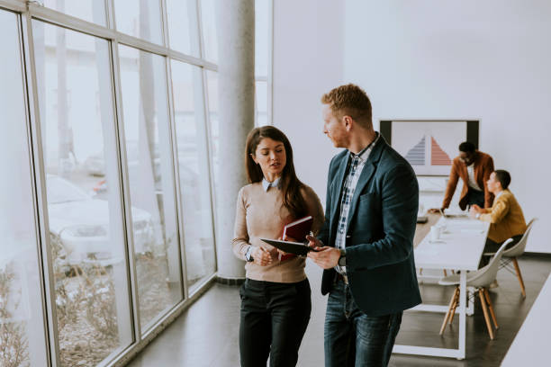 istock Young entrepreneur couple walking together and using digital tablet in the modern office 1370929995
