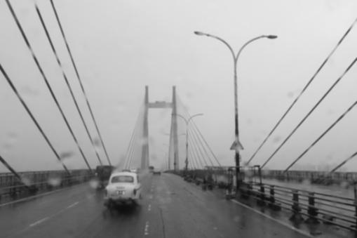 Blurred image of Howrah, West Bengal, India. Image shot through raindrops falling on car windshield , wet glass, traffic at 2nd Hoogly bridge. Monsoon black and white stock image.