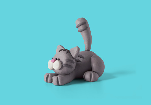Cute lying cat, handmade with gray plasticine on a blue background