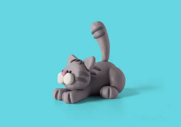 Photo of Cute lying cat, handmade with gray plasticine on a blue background