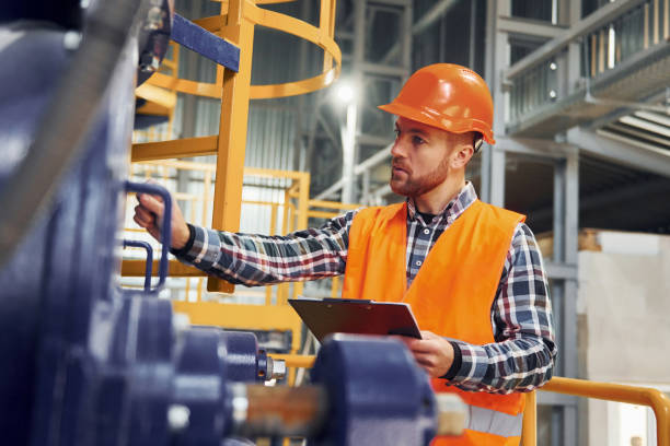 istock With notepad. Construction worker in uniform is in the factory 1370937664