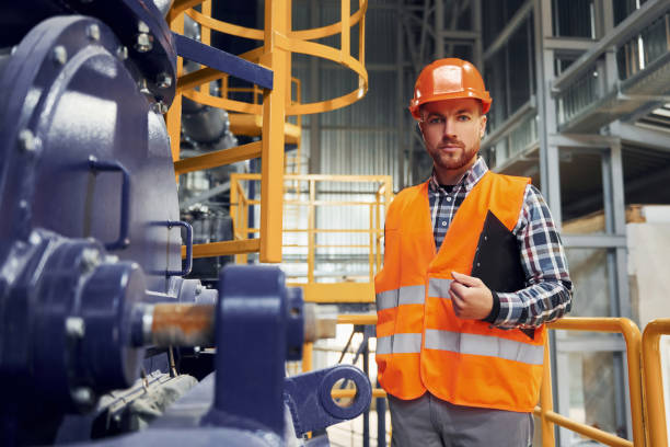 istock In orange colored hard hat. Construction worker in uniform is in the factory 1370938023