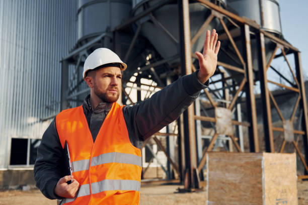 istock Showing stop gesture. Construction worker in uniform is outdoors near the factory 1370938144