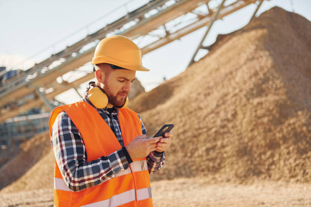 With yellow headphones on neck. Construction worker in uniform is on the quarry stock photo