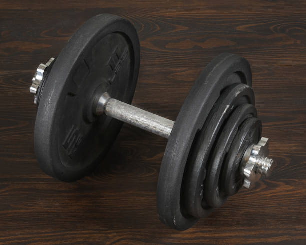 istock Black heavy dumbbell on dark wooden floor 1370938476