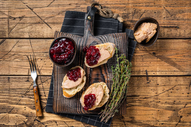 French cuisine Foie gras toasts, goose liver pate and lingonberry marmalade. wooden background. Top view French cuisine Foie gras toasts, goose liver pate and lingonberry marmalade. wooden background. Top view. foie gras stock pictures, royalty-free photos & images