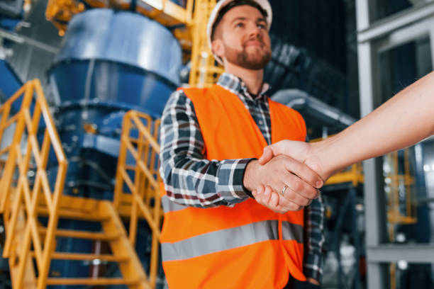 istock Making handshake with customer. Construction worker in uniform is in the factory 1370938620