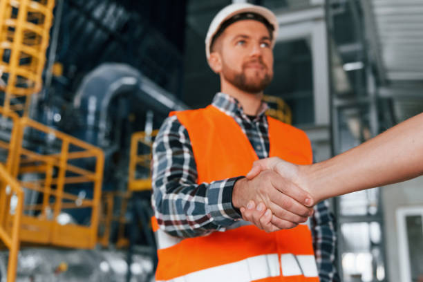 istock Making handshake with customer. Construction worker in uniform is in the factory 1370938623