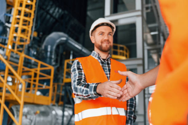 istock Making handshake with customer. Construction worker in uniform is in the factory 1370938641