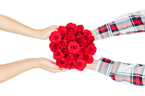 Close up of man giving a woman a bouquet of roses.