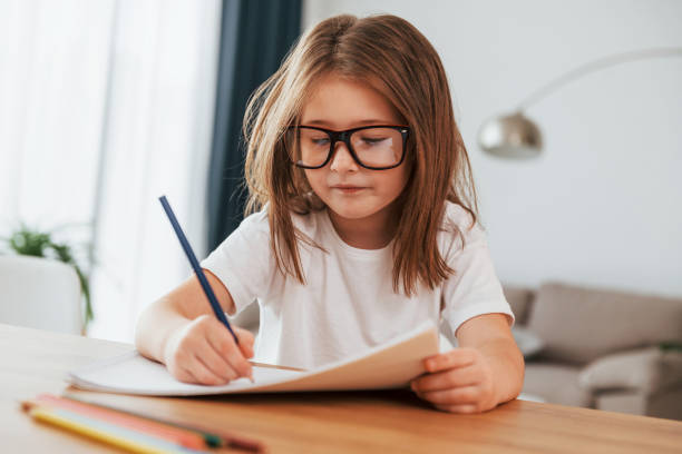 istock Little girl is sitting by the table and learning to draw 1370939892