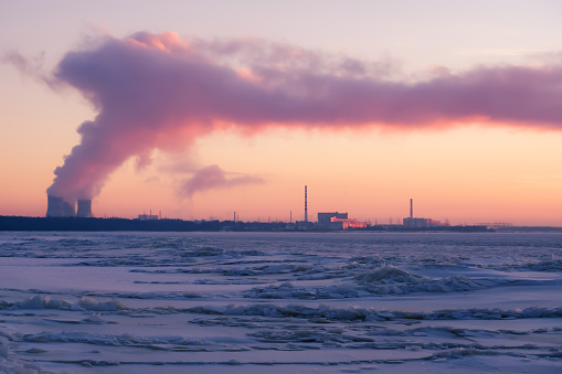 Leningrad Nuclear Power Plant on  Gulf of Finland coast in winter. Steam from evaporative cooling towers at sunset. Global warming, ecology, environmental protection, atomic energy concept.