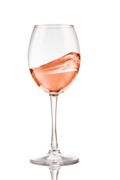 エレガントな白い背景にバラのワインの波を反映したワイングラス。 ストックフォト
