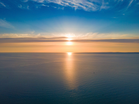 Sunset at sea - photo of a sunset over the sea horizon with the reflection of the sun in the sea and clouds in the blue sky. Beautiful seascape. Composition of nature.