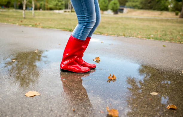 Rubber boots are jumping into a big puddle with splash.