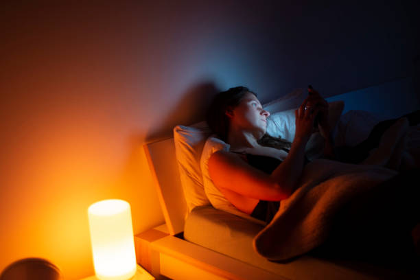 A lonely woman in her late 30's on mobile in bed. stock photo
