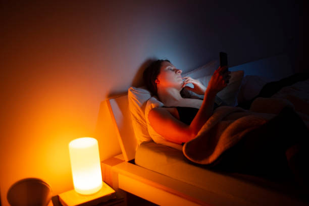 A lonely woman in her late 30's on mobile in bed. stock photo