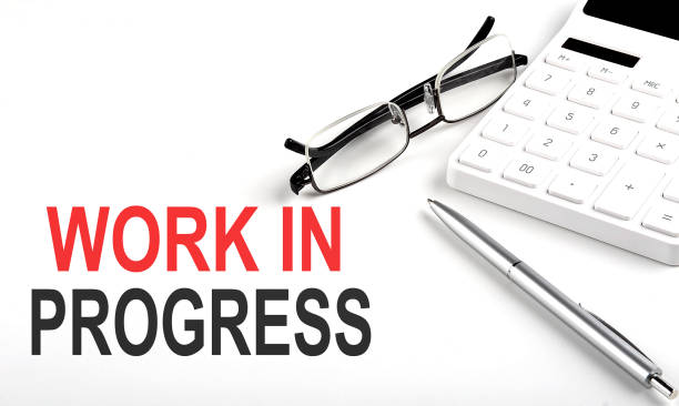 istock WORK IN PROGRESS Concept. Calculator,pen and glasses on the white background 1370951689