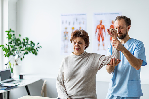 Physical therapist with patient in his medical office doing exercise