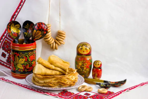 Background with pancakes, wooden utensils with Khokhloma painting, matryoshka, rushnik, sushki for Maslenitsa festival. Traditional Russian meal for Shrovetide. Greeting card or poster. Copy space.