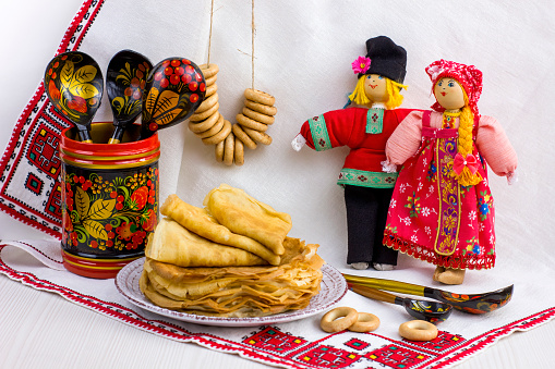Background with pancakes, textile dolls, wooden spoon, rushnik , sushki and pussy-willow for Maslenitsa festival.