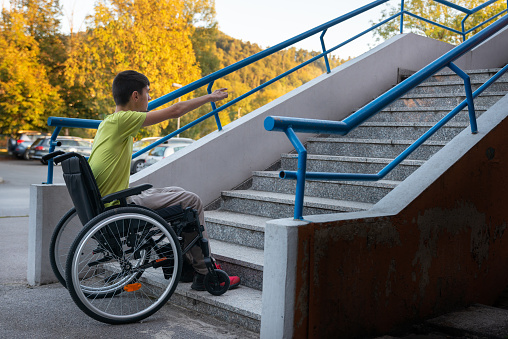 Man in wheelchair with his friend on basketball court outdoors.