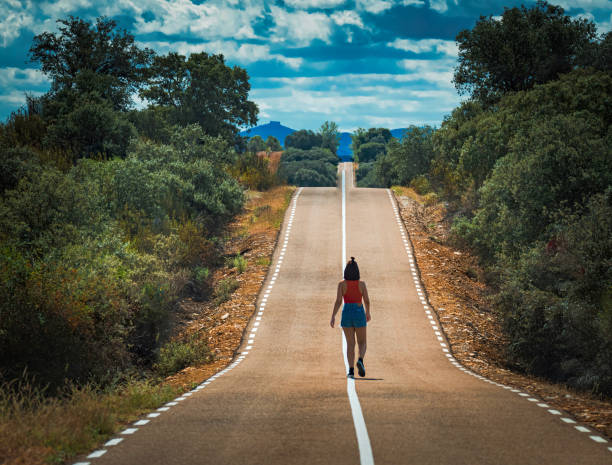 istock Woman alone on beautiful empty country bend, asphalt road. 1370964158