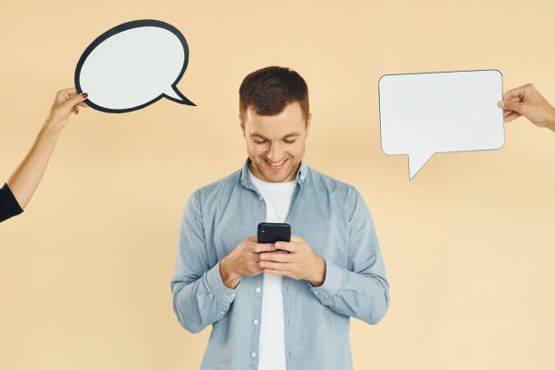 istock Holding smartphone. Many ideas. Man standing in the studio with empty signs for the text 1370966359